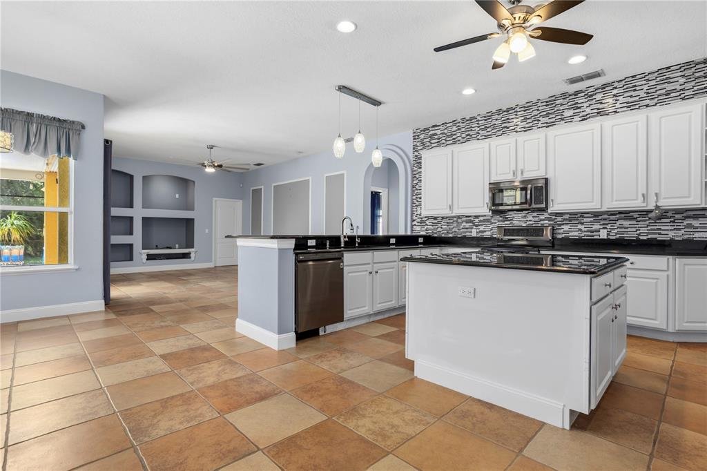 An open-concept living and dining area features light blue walls, tile flooring, and neutral furniture — 334 GRAND RESERVE DRIVE, DAVENPORT, FL