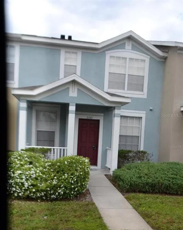 A two-story house with light blue siding, a red front door, and a covered porch — 3420 BROKEN BOW DRIVE, LAND O LAKES, FL