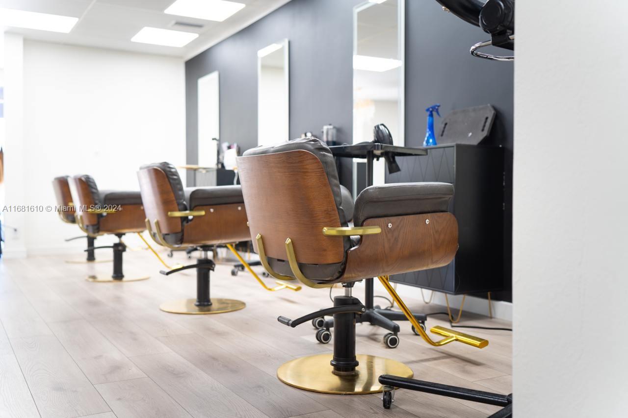 A hair salon interior features multiple styling chairs with wood accents and gold bases — FORT LAUDERDALE, FL