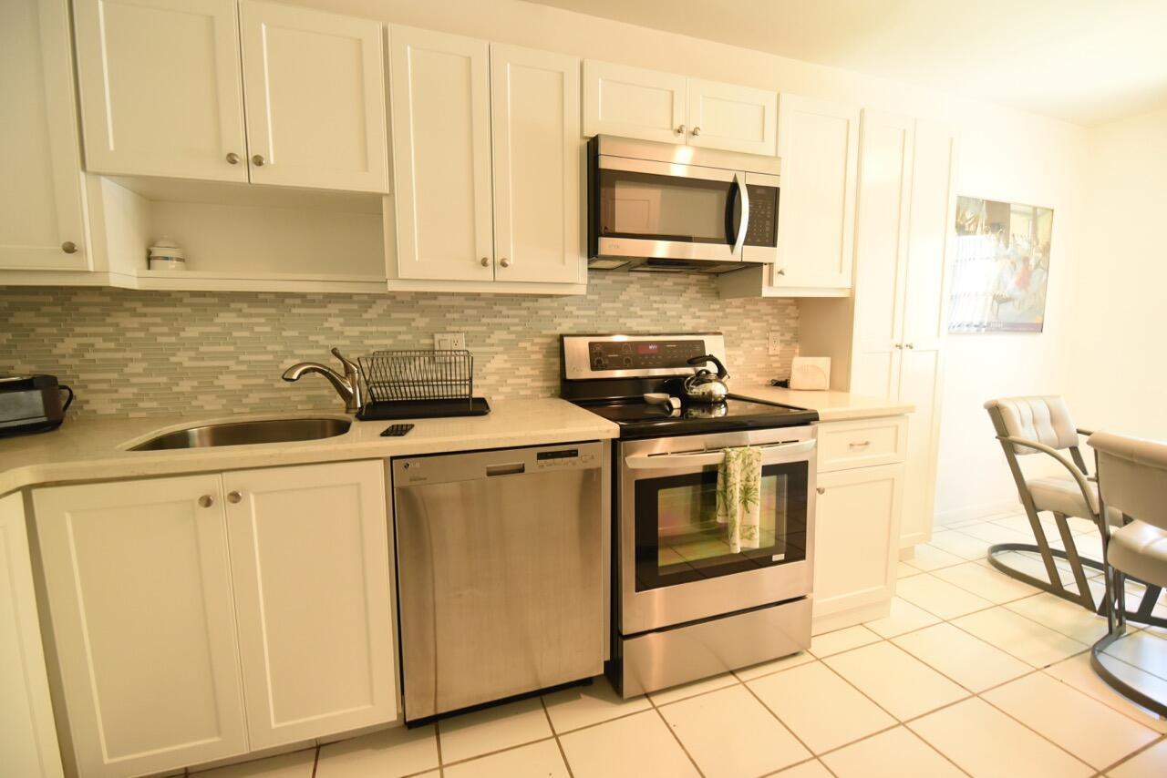 A kitchen with white cabinets, stainless steel appliances, and a light-colored tiled floor — 11 Southport Lane # H, Boynton Beach FL 33436, BOYNTON BEACH, FL