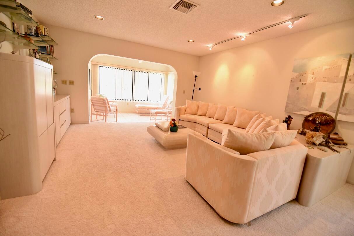 A spacious living room features beige carpeting, a large sectional sofa, and an arched entryway — 11 Southport Lane # H, Boynton Beach FL 33436, BOYNTON BEACH, FL