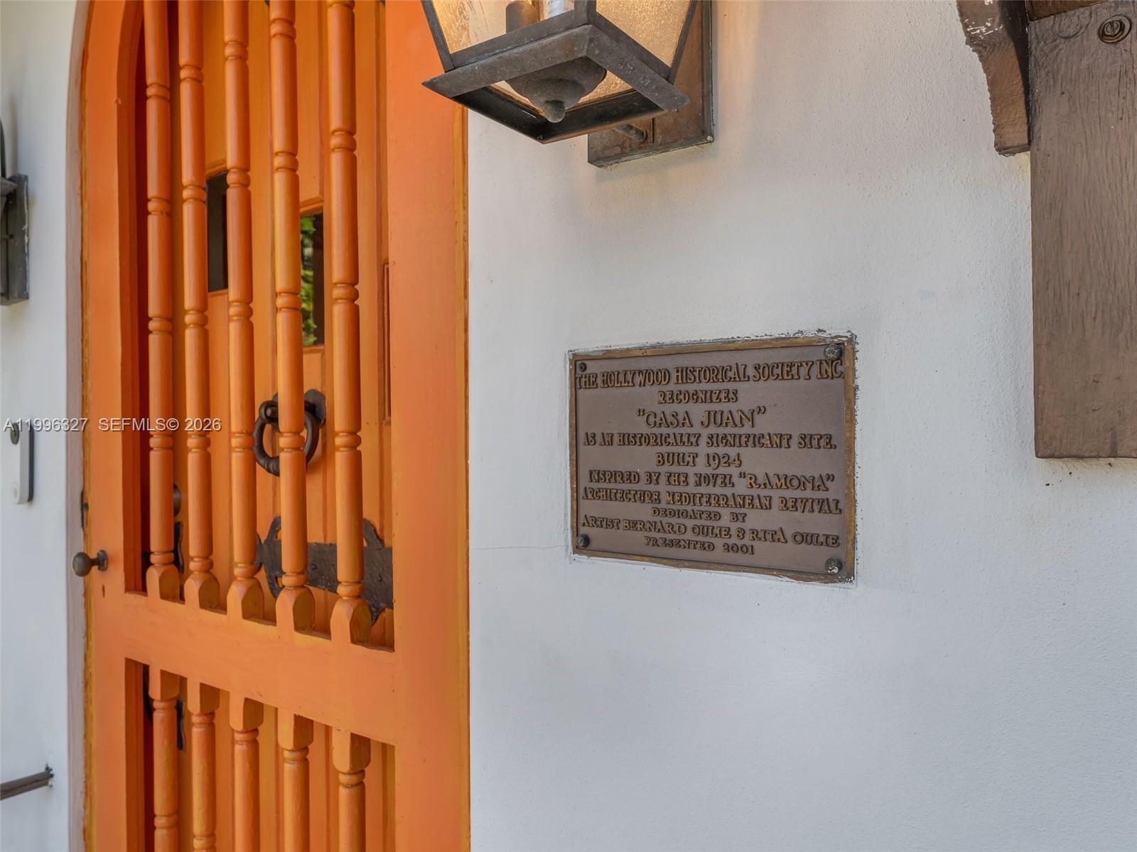 A bronze historical plaque is mounted on a white wall next to an orange door — 1321 Tyler St, Hollywood FL 33019, HOLLYWOOD, FL