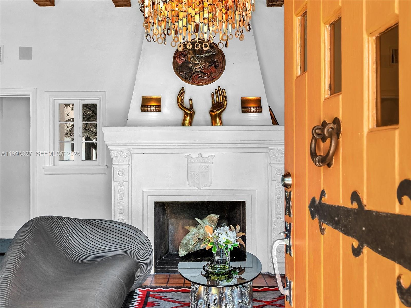 A living room features a white fireplace, a modern gray chair, and a large chandelier — 1321 Tyler St, Hollywood FL 33019, HOLLYWOOD, FL