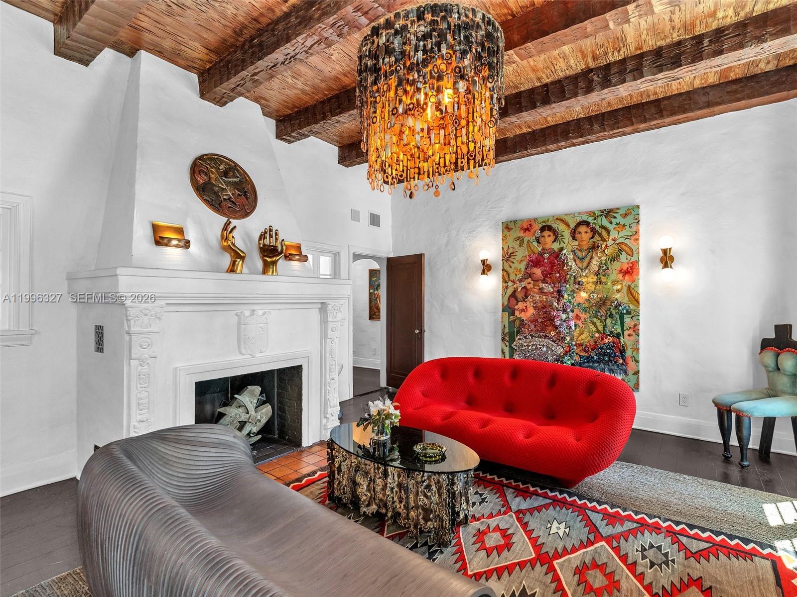A living room features a white fireplace, a red sofa, and a large chandelier — 1321 Tyler St, Hollywood FL 33019, HOLLYWOOD, FL