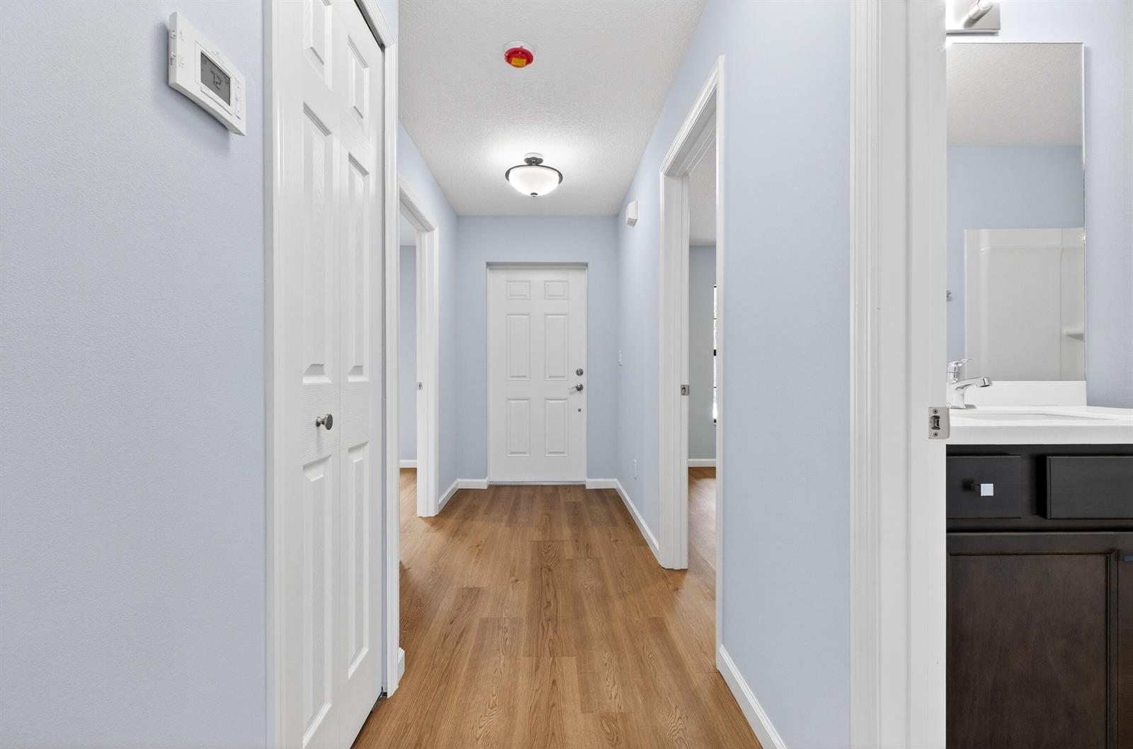 A hallway with light blue walls, wood-look flooring, and several white doors — 2875 NW 32nd Avenue, Okeechobee FL 34972, OKEECHOBEE, FL