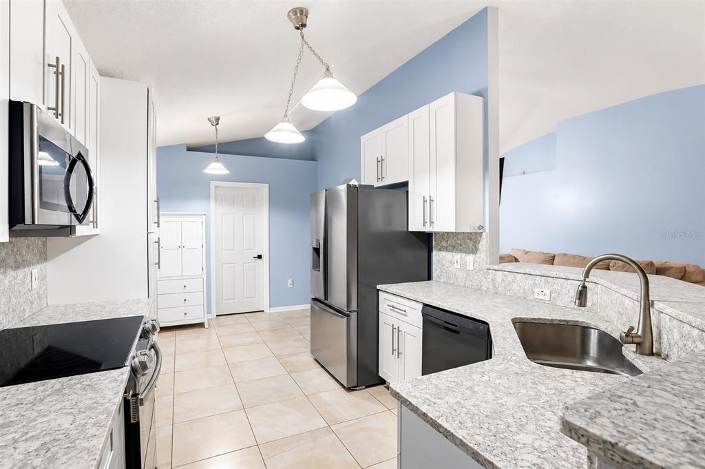 A kitchen with white cabinets, granite countertops, stainless steel appliances, and light blue walls — 2015 CORNER SCHOOL DRIVE, ORLANDO, FL