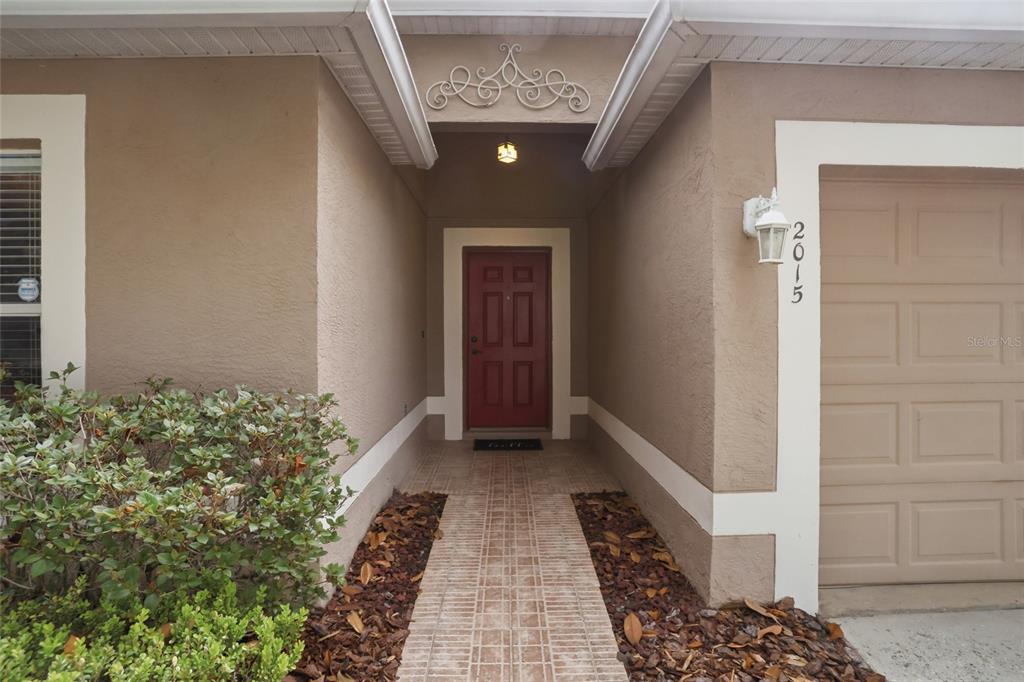 A front entryway features a red door, a brick walkway, and a tan stucco exterior — 2015 CORNER SCHOOL DRIVE, ORLANDO, FL