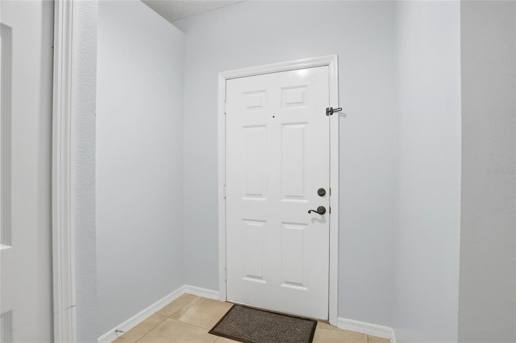 A white six-panel entry door is set against light gray walls and tiled flooring — 2015 CORNER SCHOOL DRIVE, ORLANDO, FL