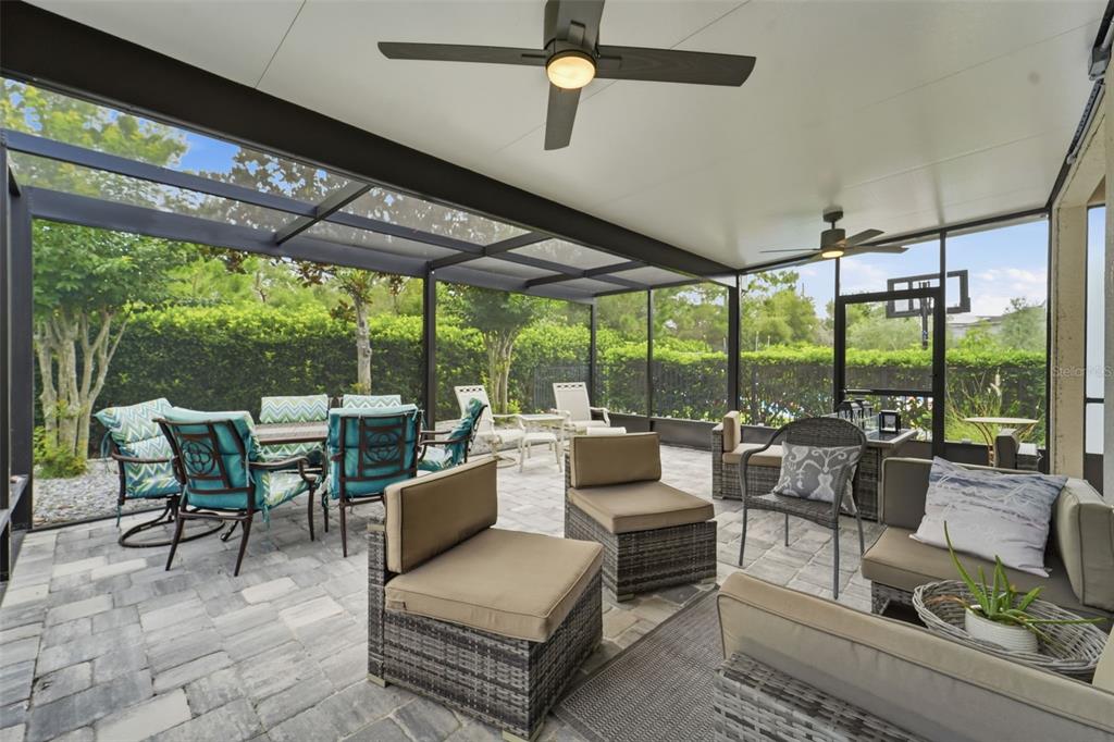 A screened-in patio features stone pavers, outdoor furniture, and two ceiling fans — 1395 RILEY CIRCLE, DELAND, FL