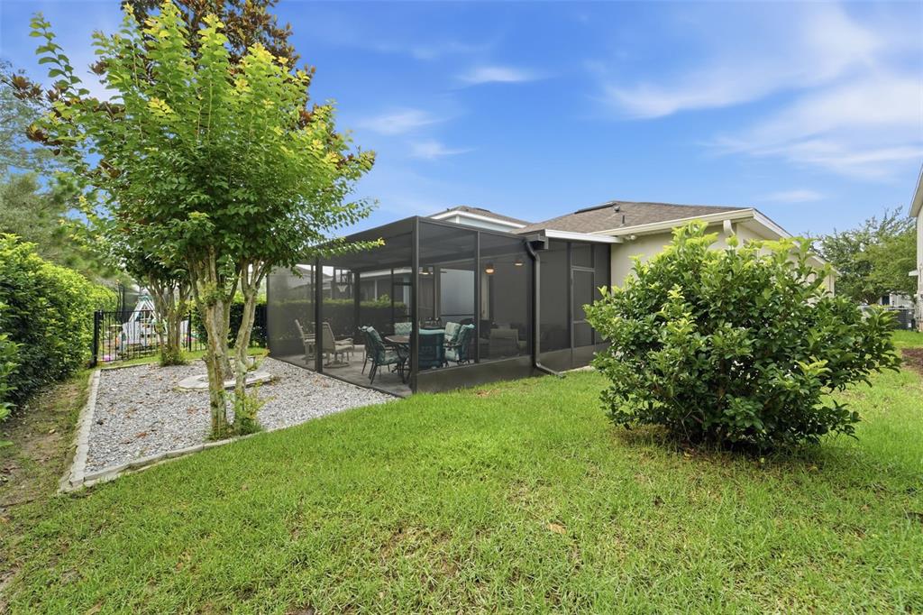 A backyard features a screened-in patio, a gravel garden bed, and a green lawn — 1395 RILEY CIRCLE, DELAND, FL