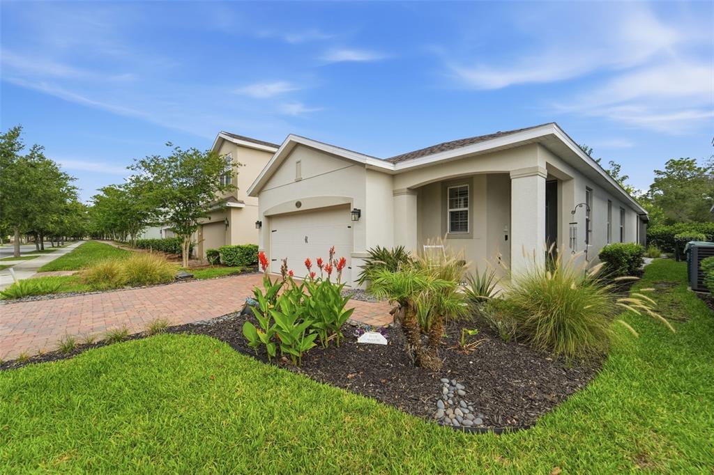 A single-story house with a beige stucco exterior, a brick driveway, and a landscaped yard — 1395 RILEY CIRCLE, DELAND, FL