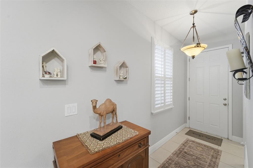An entryway features a wooden cabinet with a camel statue, wall shelves, and a pendant light — 1395 RILEY CIRCLE, DELAND, FL