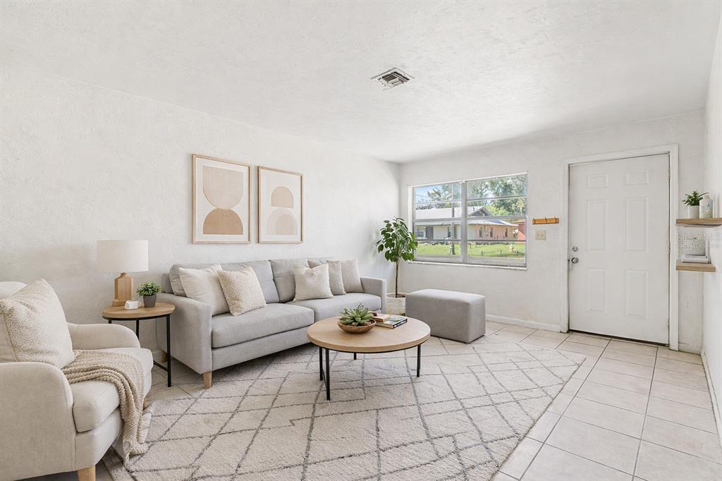 A living room with a grey sofa, armchair, round coffee table, and tile flooring — 34 NW 21ST PLACE, OCALA, FL
