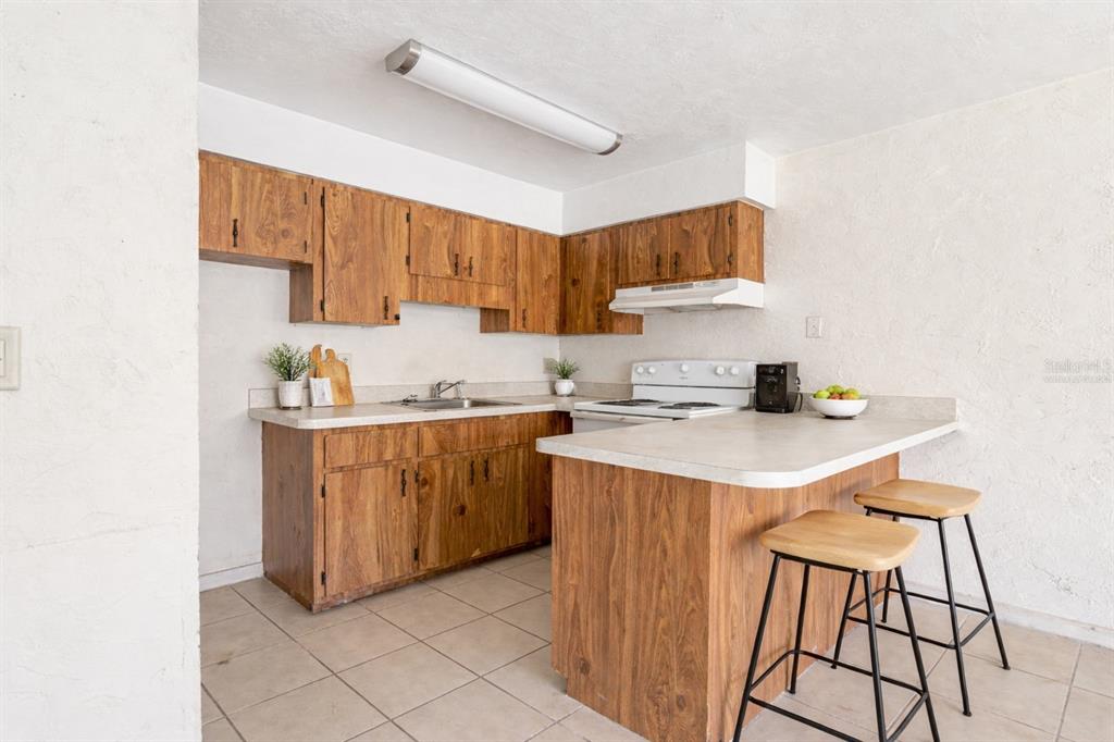 A kitchen features wood cabinets, a white countertop, a breakfast bar, and tile flooring — 34 NW 21ST PLACE, OCALA, FL