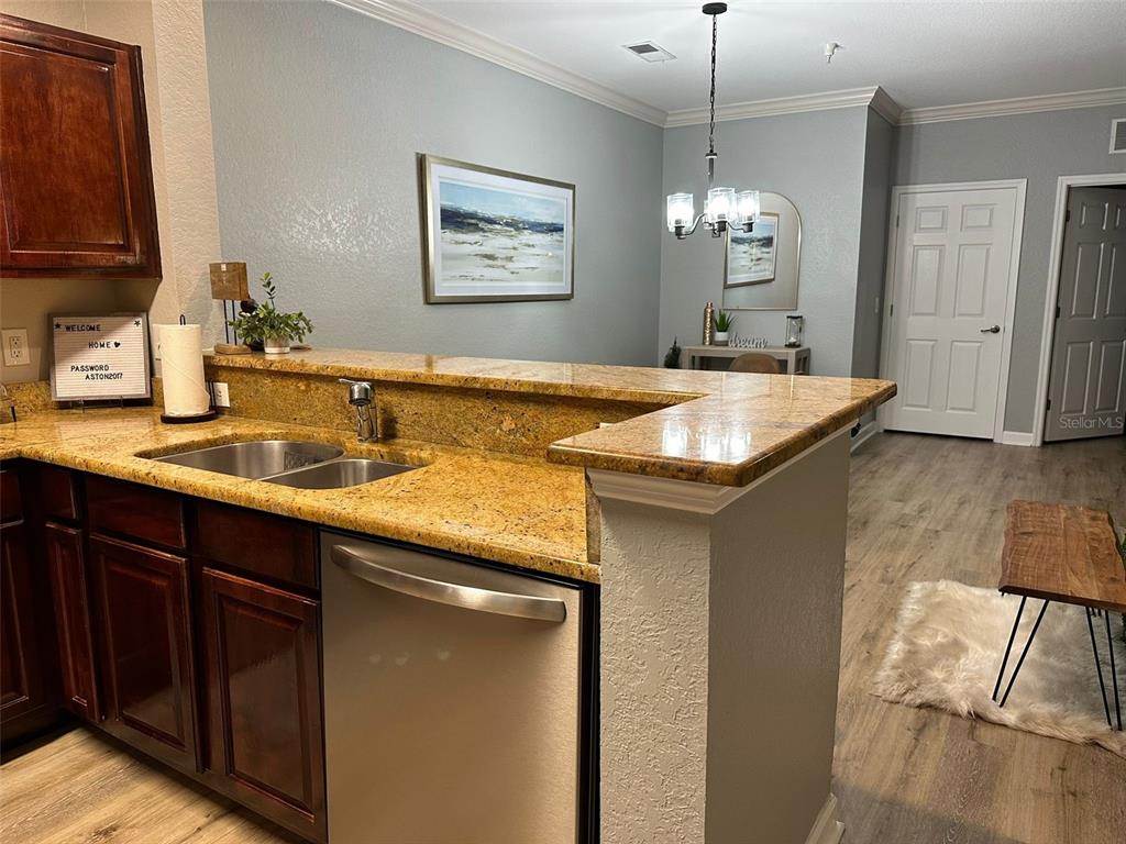 A kitchen features dark wood cabinets, granite countertops, a stainless steel dishwasher, and a dining area — 8000 TUSCANY WAY UNIT 4302, DAVENPORT, FL
