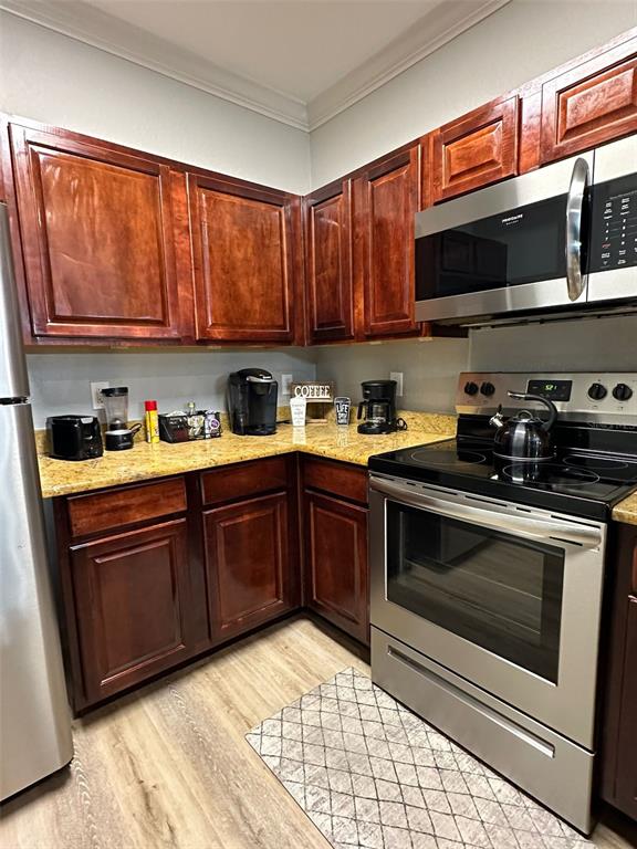 A kitchen features dark wood cabinets, granite countertops, and stainless steel appliances — 8000 TUSCANY WAY UNIT 4302, DAVENPORT, FL