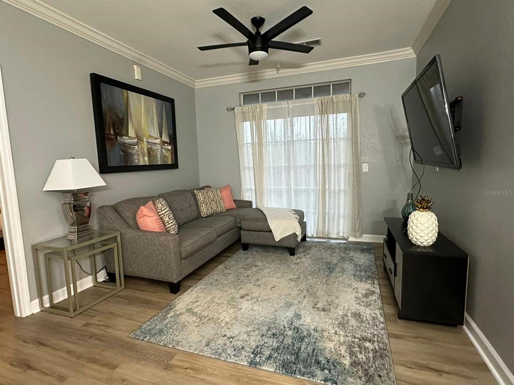 A living room features a gray sectional sofa, a patterned area rug, and a ceiling fan — 8000 TUSCANY WAY UNIT 4302, DAVENPORT, FL