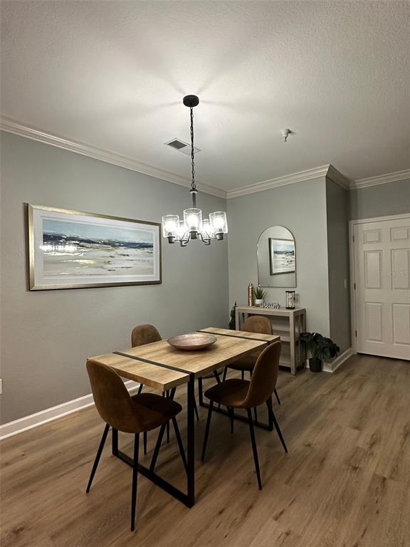 A dining room features a wooden table, four chairs, a chandelier, and wall art — 8000 TUSCANY WAY UNIT 4302, DAVENPORT, FL
