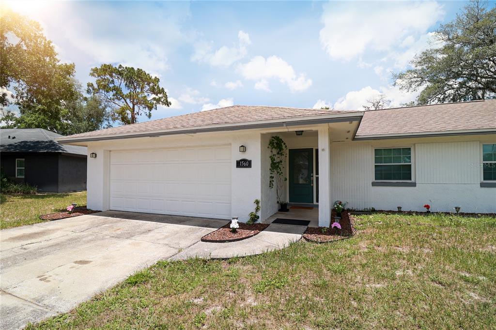 A single-story white house with a two-car garage and a front entrance under a porch — 1560 GUINEVERE DRIVE, CASSELBERRY, FL