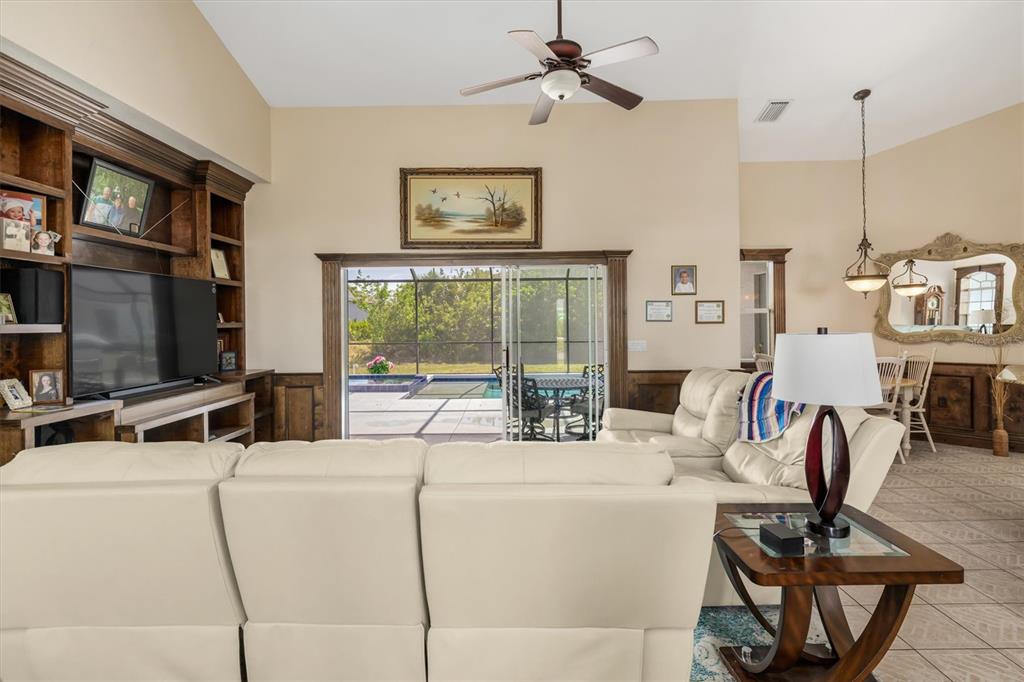 A living room features a large white sectional, built-in wooden shelving, and sliding glass doors — 10056 LEBANON DRIVE, PORT CHARLOTTE, FL