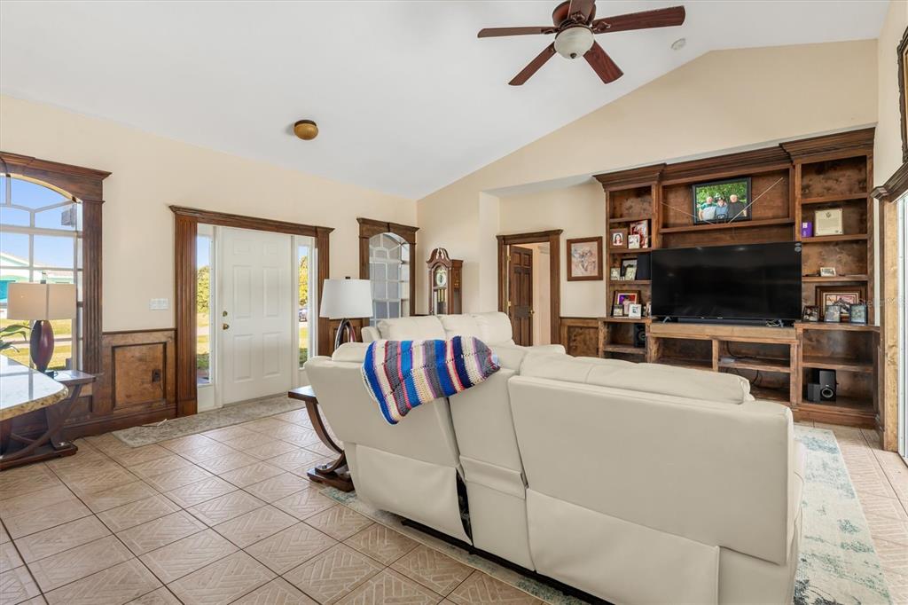 A living room features tile floors, a vaulted ceiling, and a large built-in wooden entertainment center — 10056 LEBANON DRIVE, PORT CHARLOTTE, FL