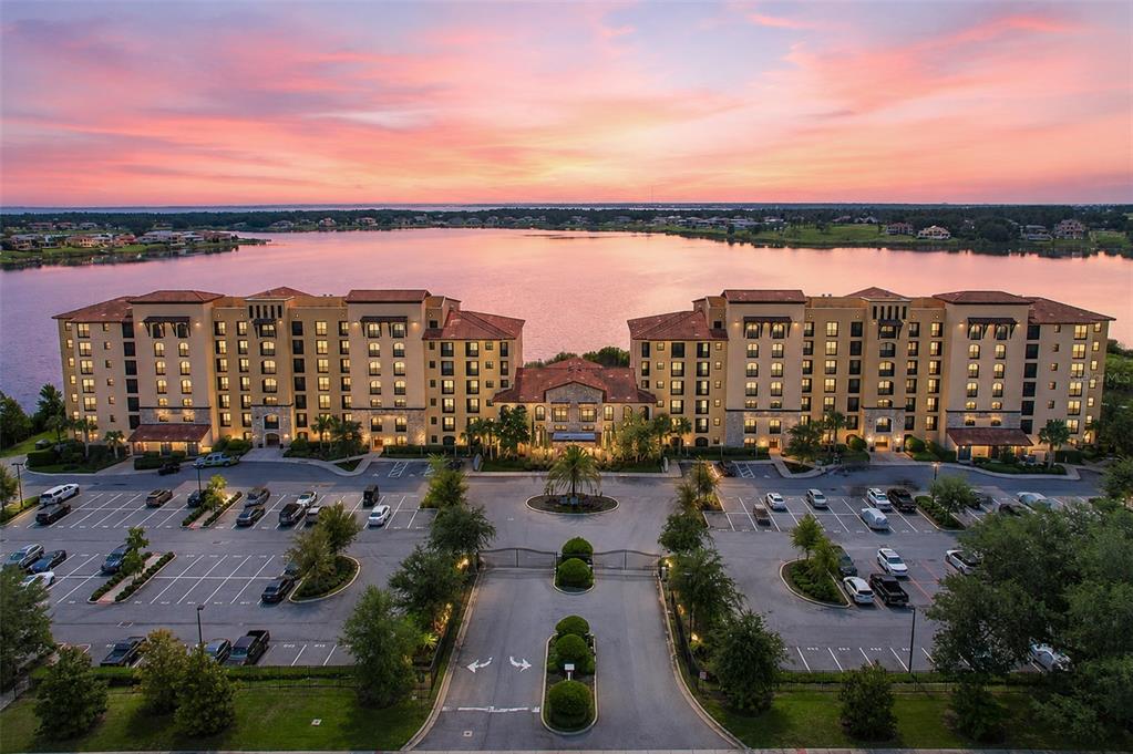 An aerial view of a multi-story apartment complex with a parking lot beside a lake — 16300 COUNTY ROAD 455 UNIT 511, MONTVERDE, FL