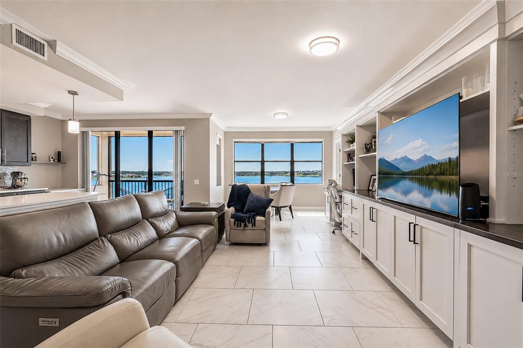 A living room with a leather sofa, built-in cabinetry, and a view of the water — 16300 COUNTY ROAD 455 UNIT 511, MONTVERDE, FL