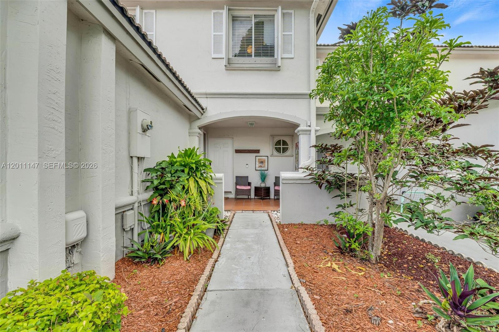 A concrete walkway leads to the covered entryway of a two-story stucco home — 16221 SW 72nd Ter, Miami FL 33193, MIAMI, FL