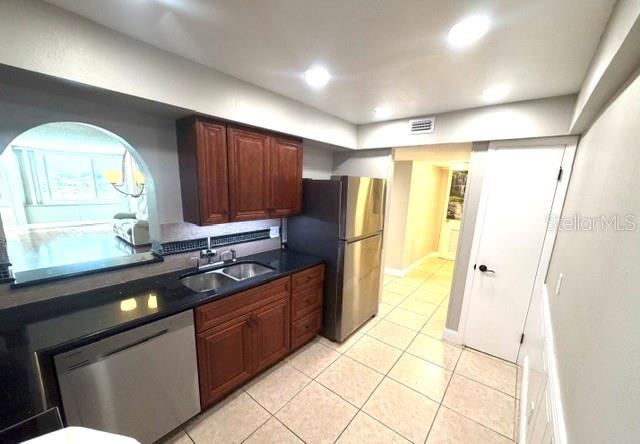 A kitchen features dark wood cabinets, stainless steel appliances, and light-colored tile flooring — 700 MIRROR TERRACE NW UNIT 507, WINTER HAVEN, FL