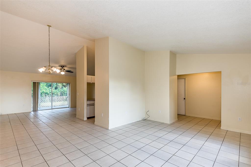 An open-concept living area features light-colored tile flooring, vaulted ceilings, and a sliding glass door — 504 VANNELL STREET, PORT CHARLOTTE, FL