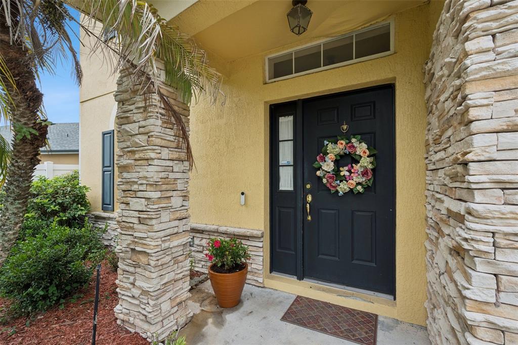 A front entryway features a black door with a floral wreath, stone pillars, and stucco — 12202 ACCIPITER DRIVE, ORLANDO, FL