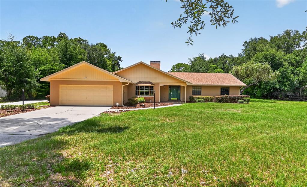 A single-story house with a tan exterior, a two-car garage, and a large front lawn — 815 LAKE NED ROAD, WINTER HAVEN, FL