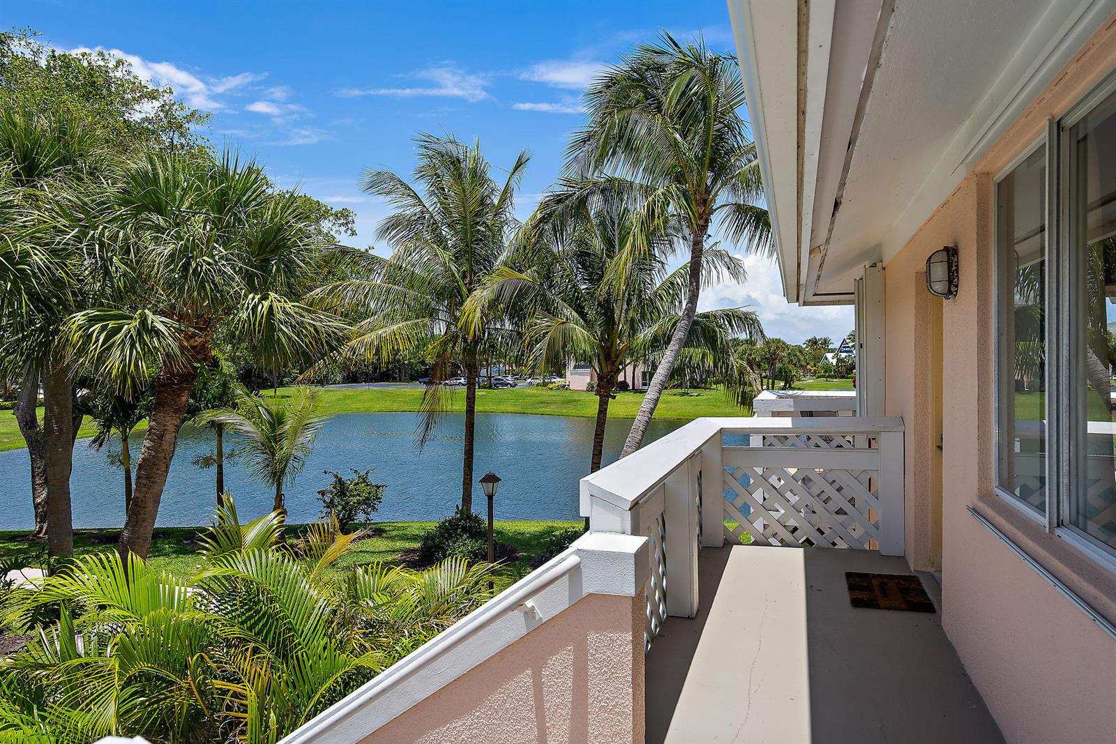 A balcony with a white railing overlooks a pond surrounded by palm trees and grass — 353 S Us Hwy 1 # A8, Jupiter FL 33477, JUPITER, FL