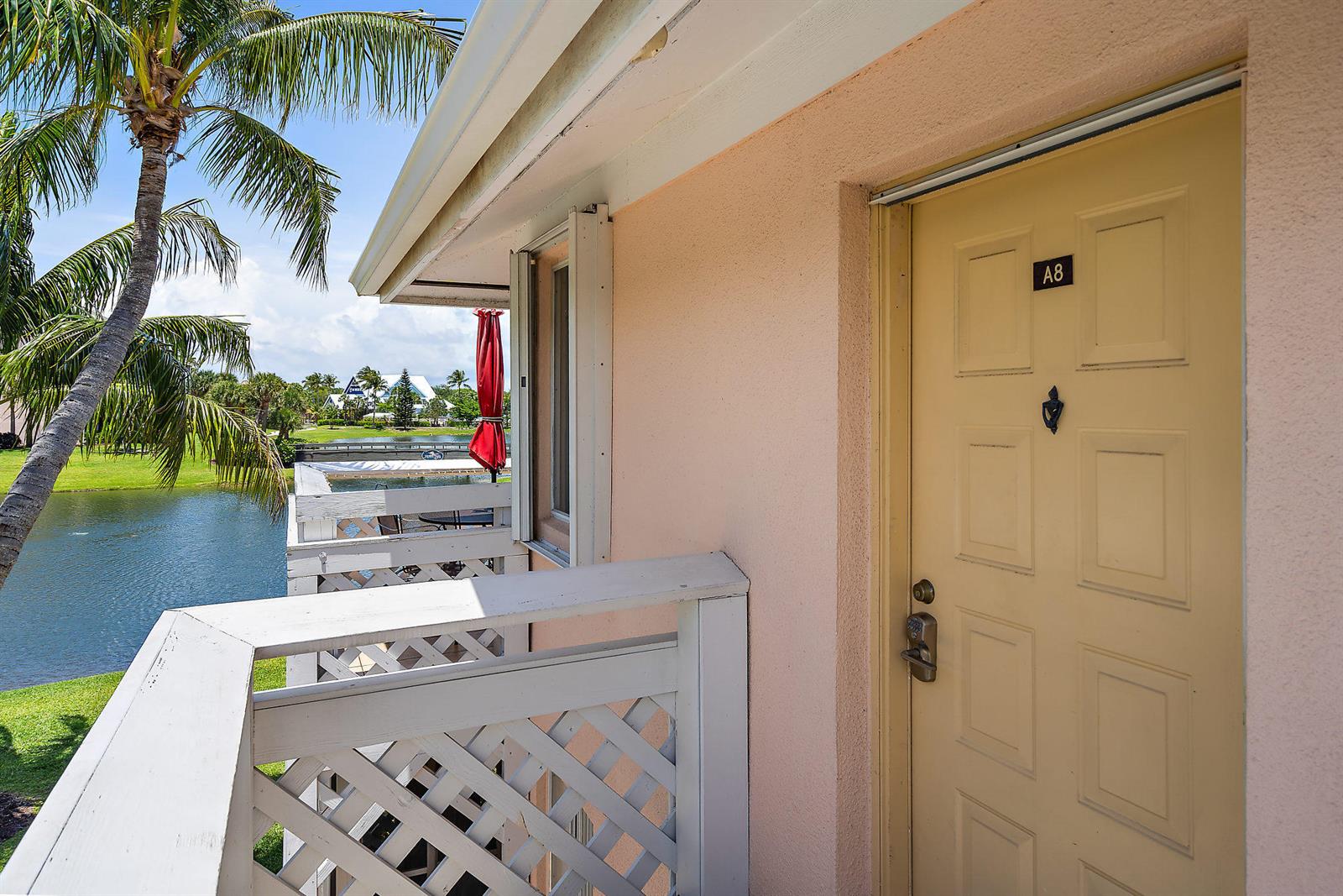 A view of a balcony with a white railing overlooking a pond and palm tree — 353 S Us Hwy 1 # A8, Jupiter FL 33477, JUPITER, FL