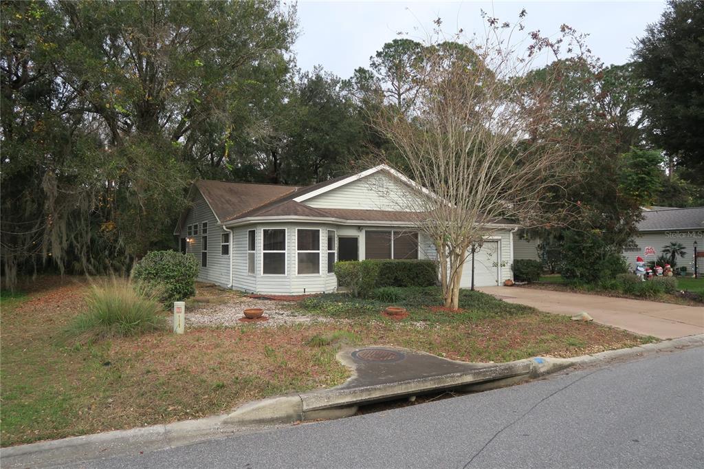 A single-story house with light siding, a bay window, and a driveway sits on a lot — 32512 OAK PARK DRIVE, LEESBURG, FL