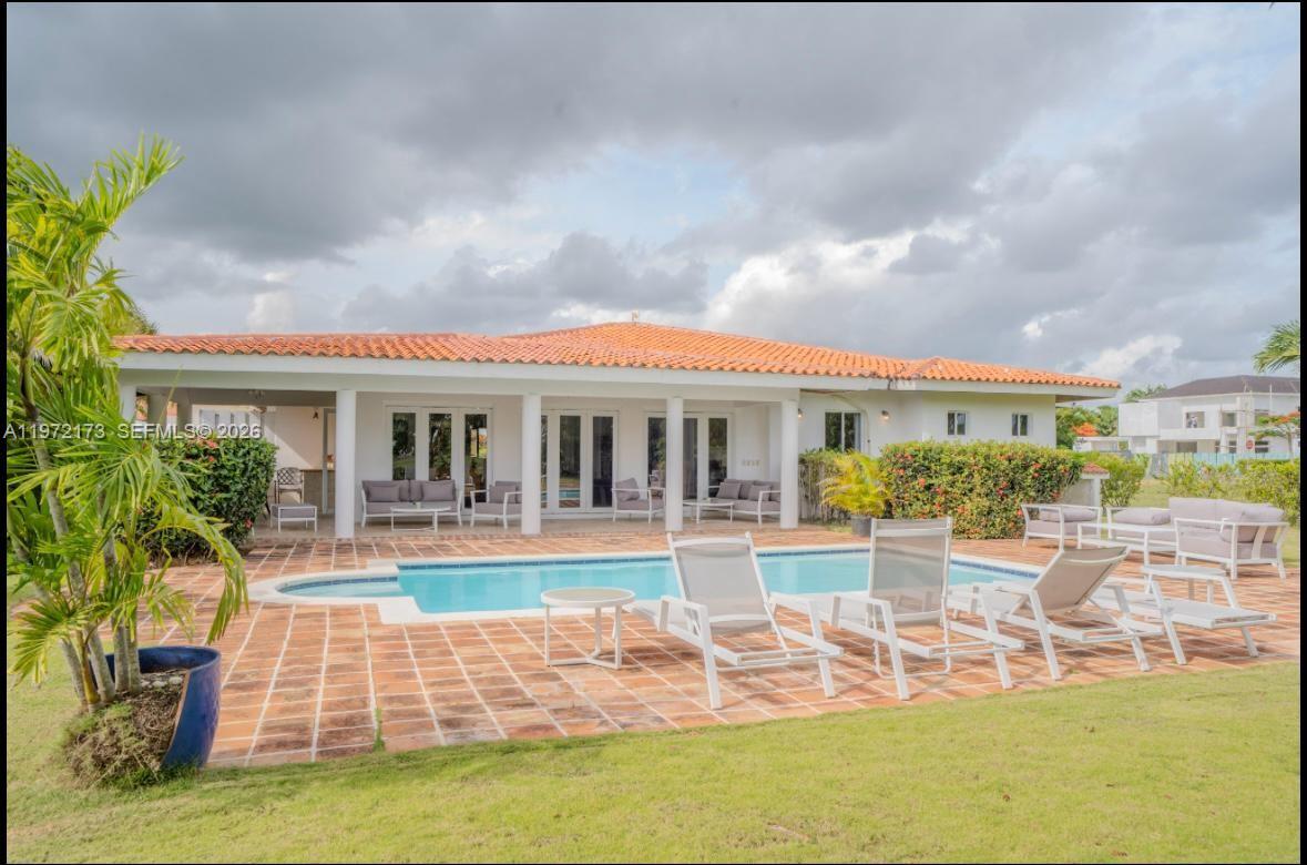 A backyard features a swimming pool, a tiled patio, and a house with a terracotta roof — Los Samanes La Estancia, DR 0, DR