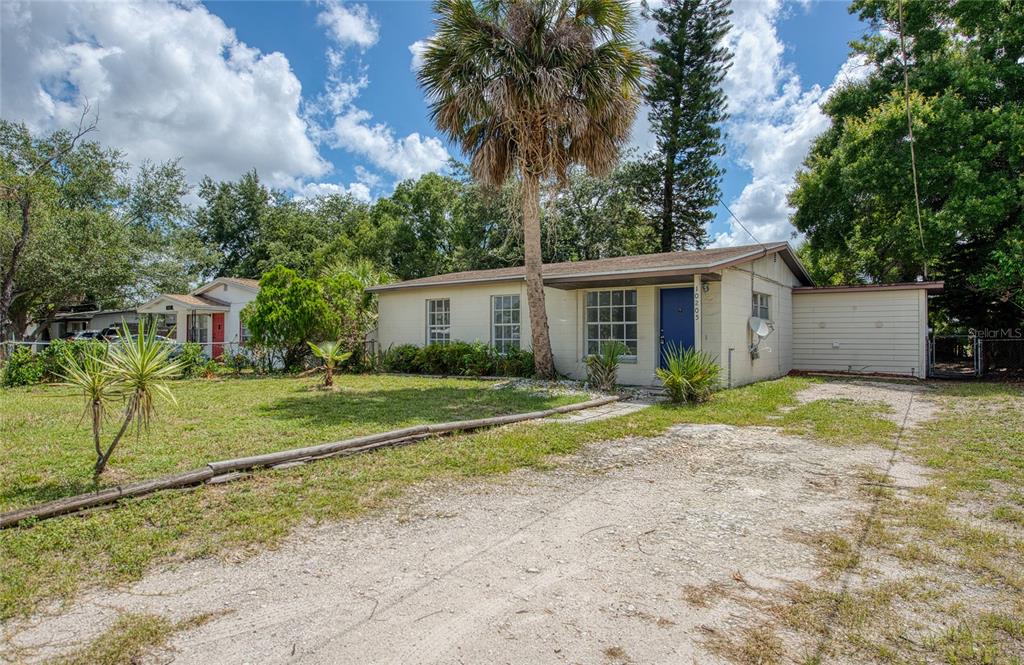 A single-story house with a blue front door, a palm tree, and a gravel driveway — 10205 N 29TH STREET, TAMPA, FL
