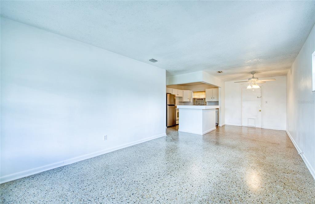 An open-concept living area features white walls, a breakfast bar, and speckled terrazzo flooring — 10205 N 29TH STREET, TAMPA, FL