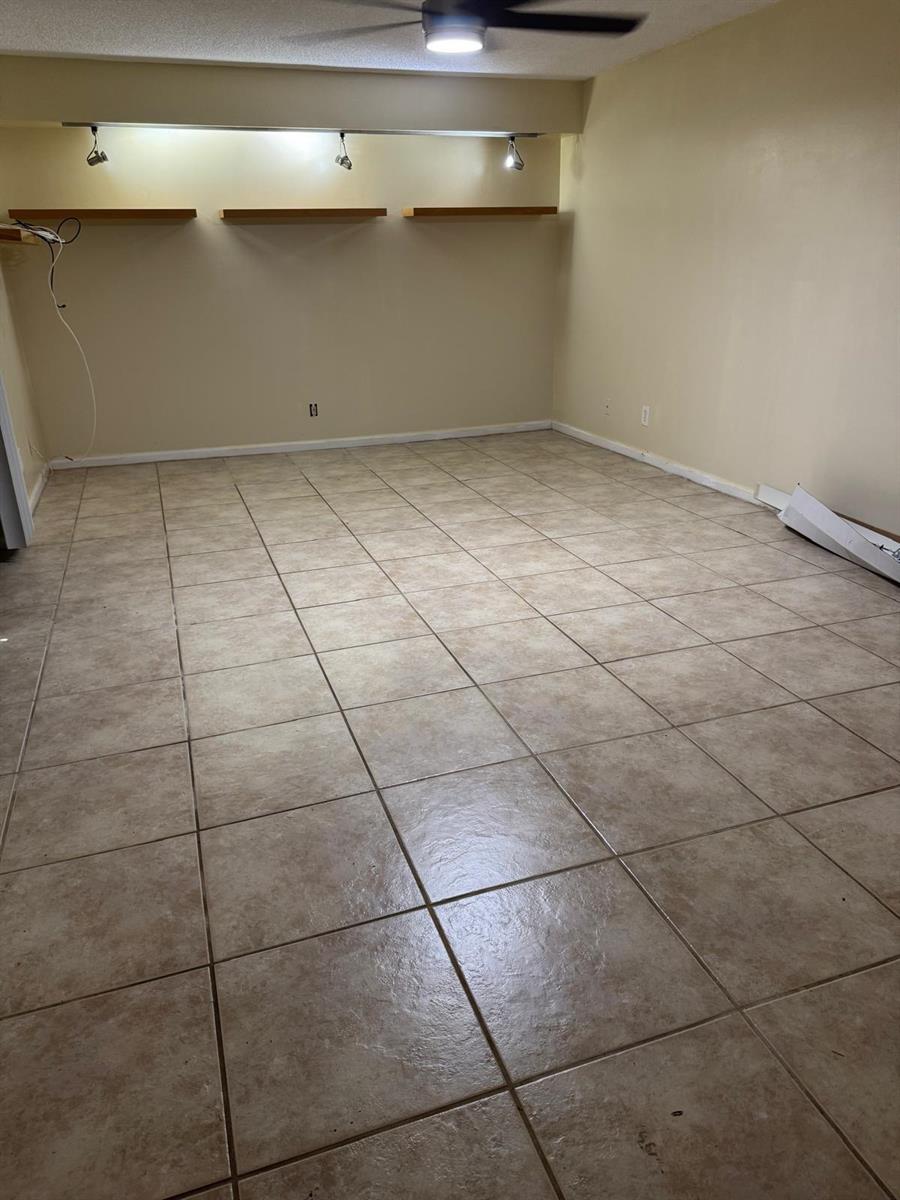 An empty room features beige tile flooring, a ceiling fan, and three wall-mounted floating shelves — 730 NW 98th Circle, Plantation FL 33324, PLANTATION, FL