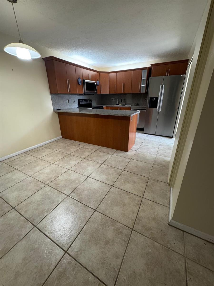 A kitchen with wood cabinets, granite countertops, stainless steel appliances, and tiled flooring — 730 NW 98th Circle, Plantation FL 33324, PLANTATION, FL