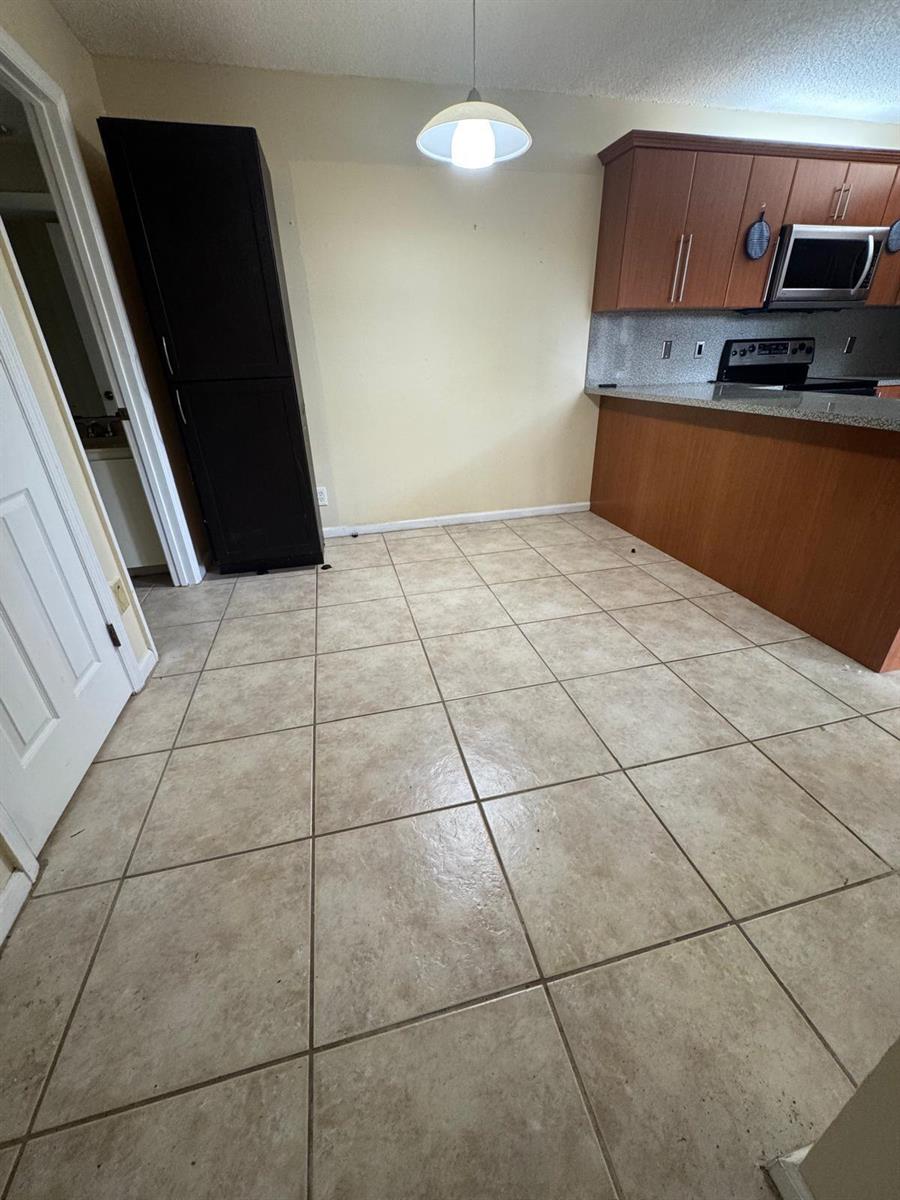 A dining area with beige tile flooring, a pendant light, and a dark tall cabinet — 730 NW 98th Circle, Plantation FL 33324, PLANTATION, FL