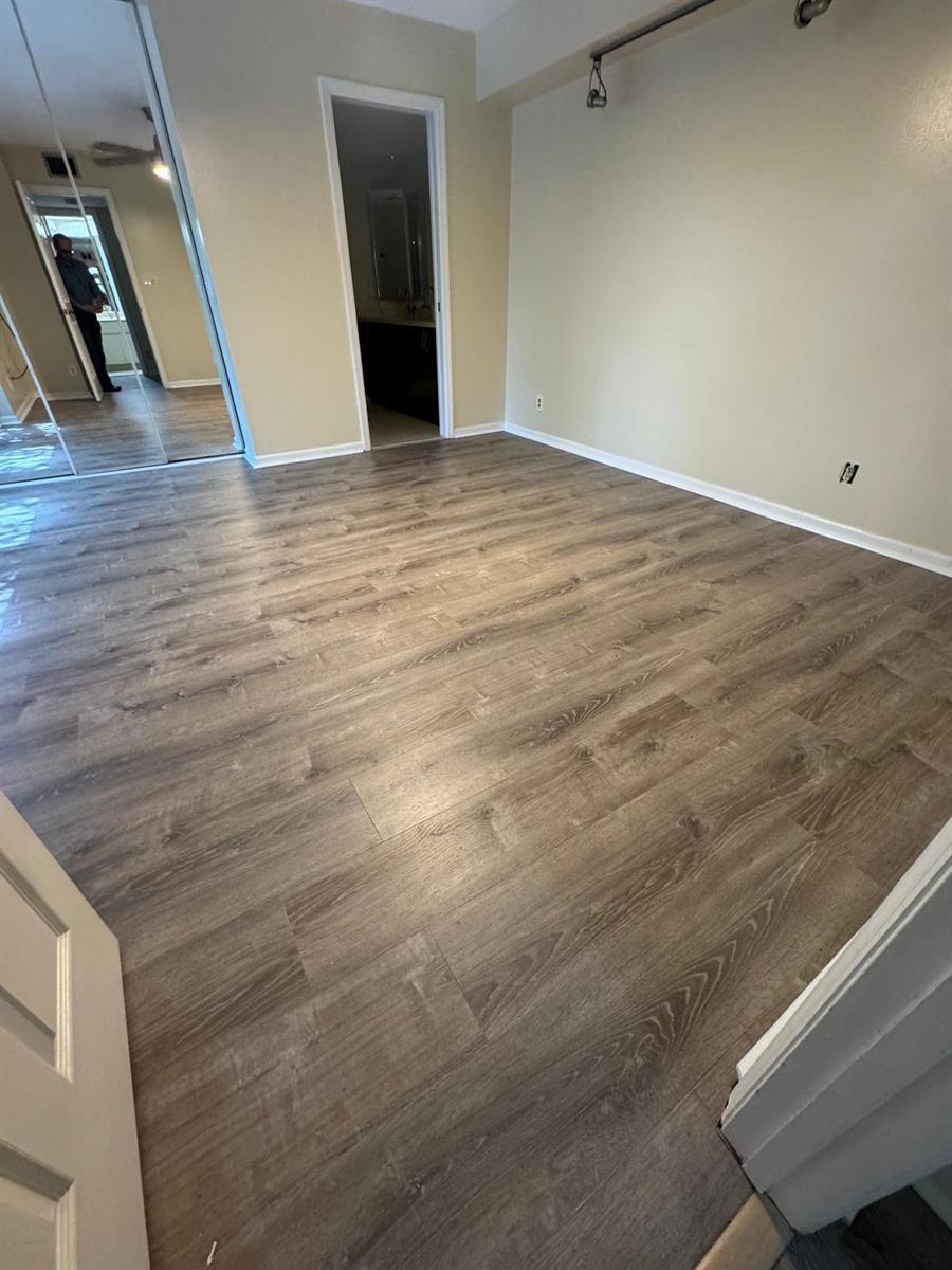 An empty bedroom features wood-look laminate flooring, beige walls, and a mirrored closet door — 730 NW 98th Circle, Plantation FL 33324, PLANTATION, FL