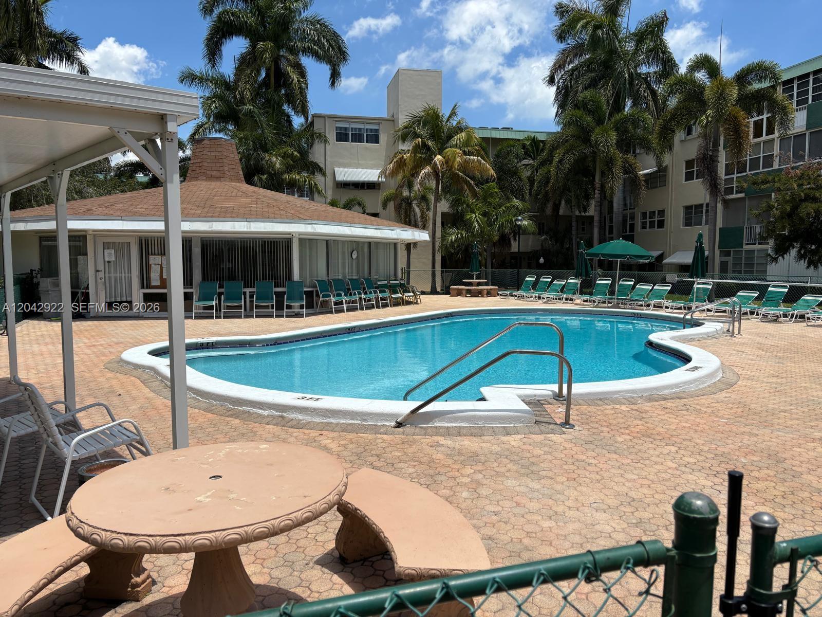 An outdoor swimming pool is surrounded by a paved deck, lounge chairs, and palm trees — 1333 E Hallandale Beach Blvd # 134, Hallandale Beach FL 33009, HALLANDALE BEACH, FL