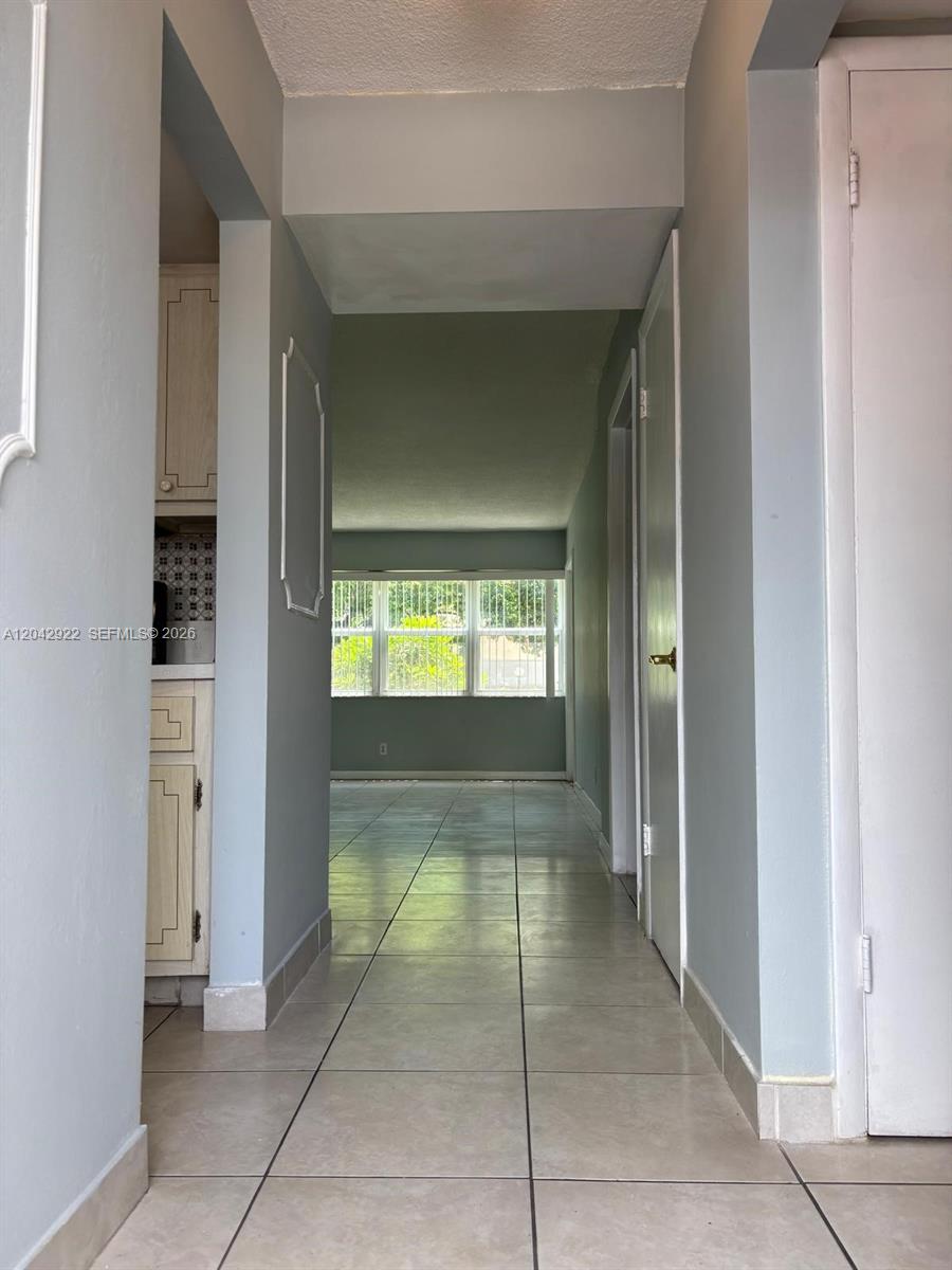 A tiled hallway leads past a kitchen toward a room with large windows — 1333 E Hallandale Beach Blvd # 134, Hallandale Beach FL 33009, HALLANDALE BEACH, FL