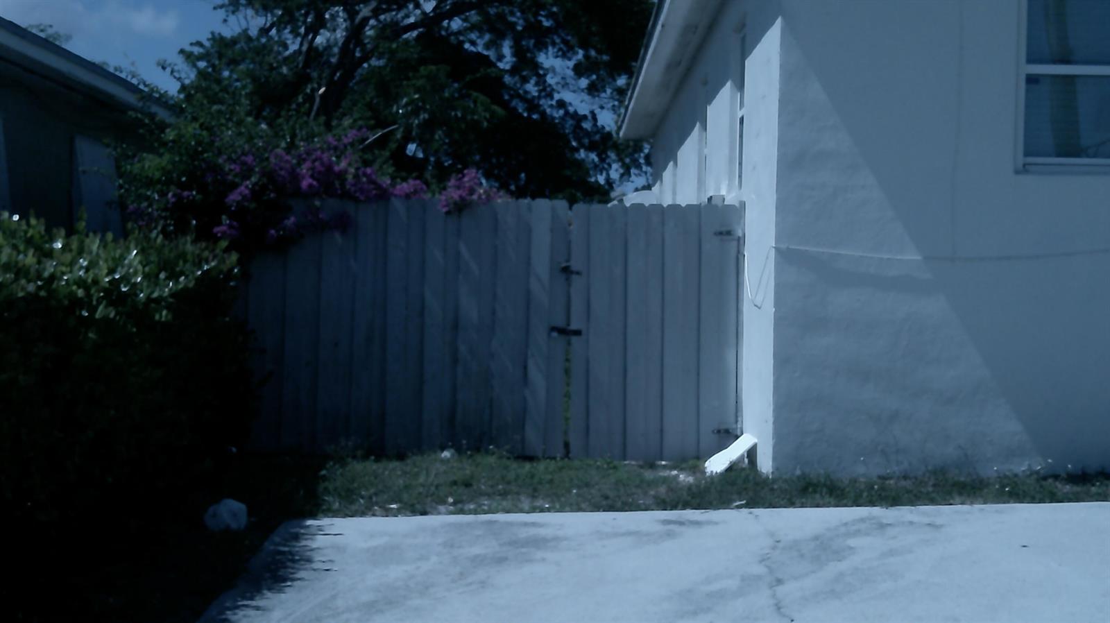 A white wooden fence stands next to the side of a white house — 900 W 9th Street, Riviera Beach FL 33404, RIVIERA BEACH, FL
