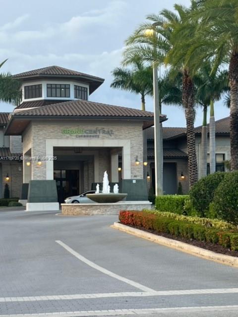 The exterior of a building features a stone facade, a fountain, and palm trees — 10630 NW 88th St # 103, Doral FL 33178, DORAL, FL