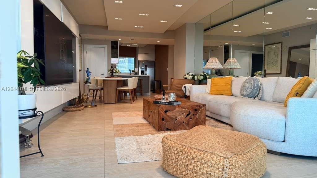 A modern living room features a large television, a wooden coffee table, and white sofas — 601 NE 36th St # 1306, Miami FL 33137, MIAMI, FL