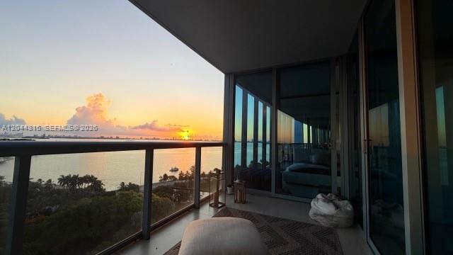 A balcony with a glass railing overlooks a sunset over the water — 601 NE 36th St # 1306, Miami FL 33137, MIAMI, FL
