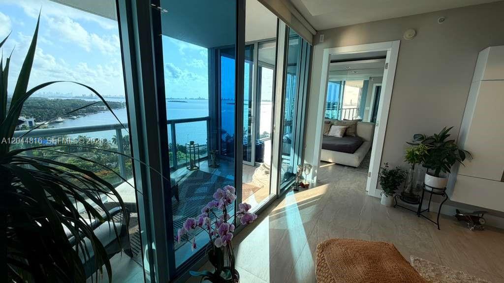 A bright living area with floor-to-ceiling windows, a balcony, and a view of the water — 601 NE 36th St # 1306, Miami FL 33137, MIAMI, FL