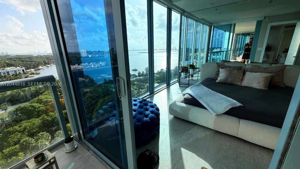 A bedroom with floor-to-ceiling windows overlooks a coastal view and features a platform bed — 601 NE 36th St # 1306, Miami FL 33137, MIAMI, FL